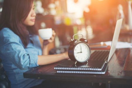 mulher tomando café mexendo no notebook dicas de produtividade e gestão de tempo cleverson lacerda